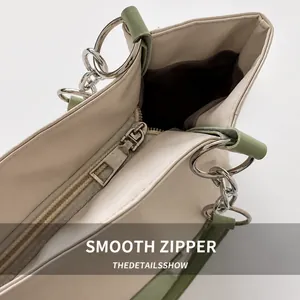 Close-up of smooth silver metal zipper and cream leather detail on large tote bag
