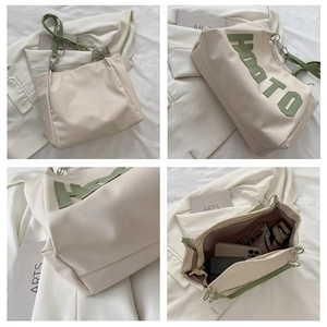 Close-up of a cream tote bag featuring green HOOTO lettering and metal chain strap details
