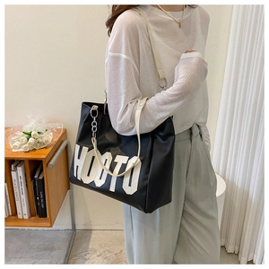 Close-up of black leather tote bag featuring white HOOTO lettering and a wide shoulder strap
