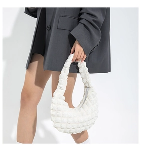 Detail of white popcorn textured crescent handbag showing bubbly 3D fabric and strap