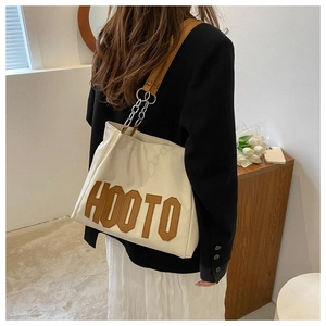 Detail of off-white canvas tote with brown HOOTO embroidery and leather chain strap