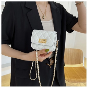 Weiße Mini-Umhängetasche mit Steppmuster, Goldschloss und Kettenriemen am schwarzen Blazer