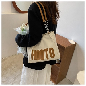 Detail of cream tote bag with brown HOOTO embroidery and leather shoulder strap