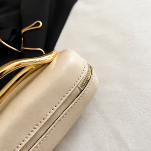 Detailed macro view of beige leather evening bag corner with golden zipper and metal handle