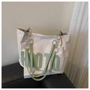 Detail of white tote bag with green 3D HOTO letters and silver chain shoulder strap