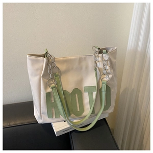 Detail of canvas tote bag featuring green HOTD 3D letters and metal chain handles