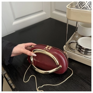 Detail of burgundy oval evening bag with large gold horseshoe handle and snake chain