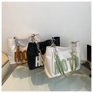 Close-up of three stylish tote bags in various colors with metallic chain straps