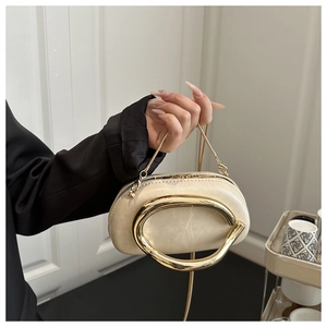 Detail of cream evening bag with a prominent gold metal ring handle and chain strap
