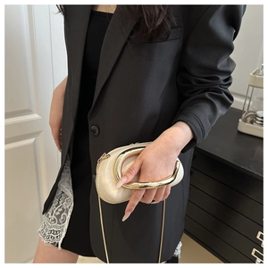Close-up of cream leather evening bag featuring a large U-shaped gold metal handle