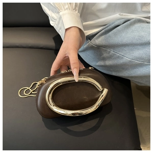 Close-up of a dark brown clutch bag with a large gold metal ring and chain strap