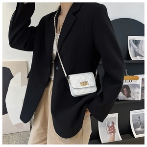 Detail einer weißen Stepptasche mit goldenem Drehverschluss und Kettenriemen