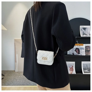 Detail einer weißen gesteppten Mini-Umhängetasche mit Metalldrehverschluss und Kette