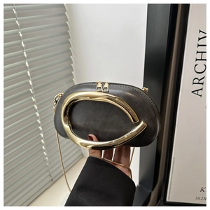 Detail of dark grey leather evening clutch with large C-shaped gold handle and chain