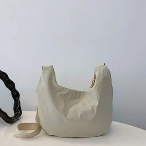 Bolso bandolera minimalista de nailon beige en forma de media luna con textura rugosa