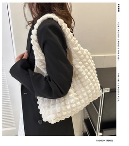 Detailed texture of white bubble textured tote bag worn by a model in black blazer