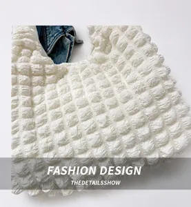Detailed macro view of white popcorn bubble texture fabric and handle stitching on tote bag