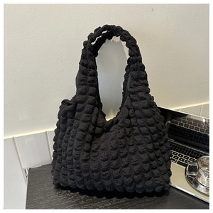 Close-up of black bubble textured fabric on a large shoulder tote bag in an office setting