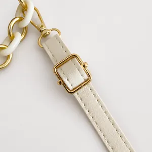 Détail de la bandoulière réglable crème avec boucle dorée et chaîne en résine