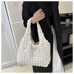 Detail of white bubble texture handbag styled with a black blazer and white skirt