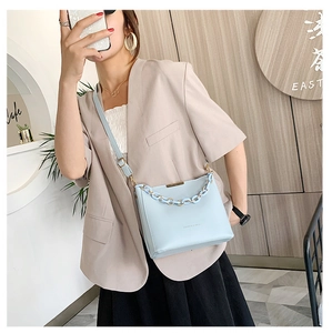 Sac seau bleu ciel à chaîne porté sur un mannequin avec blazer beige et jupe