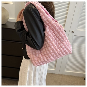 Close-up of pink popcorn textured handbag showing the pleated fabric detail and shoulder strap
