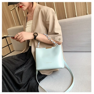 Détail du sac seau bleu clair avec bordure dorée et poignée en chaîne résine
