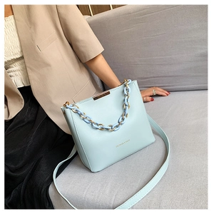 Détail du sac seau trapèze bleu clair avec chaîne acrylique et accents dorés