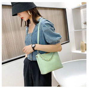 Vue détaillée du sac seau vert menthe avec anse en chaîne épaisse et logo texte tendance