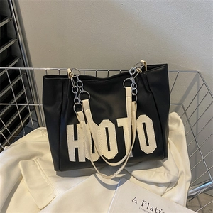 Black leather tote bag with white HOOTO lettering and metal chain straps on display