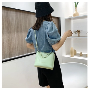 Détail du sac bandoulière vert menthe avec chaîne dorée et texture en cuir lisse élégant