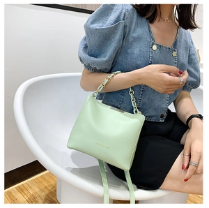 Détail du sac seau vert menthe avec chaîne dorée et bandoulière en cuir élégante