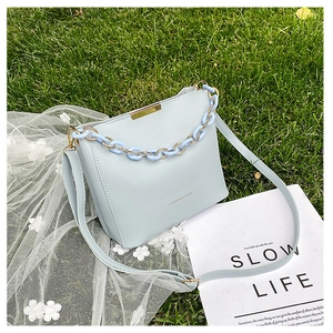 Sac seau bleu clair avec anse chaîne sur herbe avec magazine de mode en arrière plan