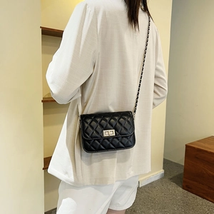 Klassische schwarze Stepptasche mit goldener Kette und Verschluss am Modell
