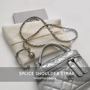 Close-up of silver quilted cylinder bag featuring a chain strap and floral metal charm