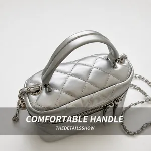Detailed top view of silver quilted cylinder bag with dual zippers and padded handle