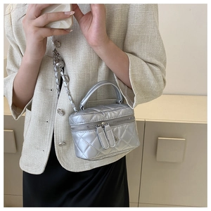 Silver quilted mini barrel bag with metal chain strap and decorative floral charm detail