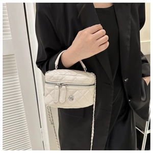 Close-up of quilted cream mini bag with camellia detail and chain strap worn by a model