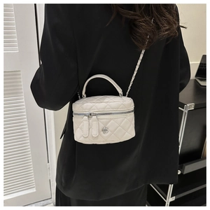 Side view of model wearing a white quilted mini crossbody bag with silver chain strap