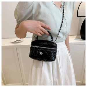 Petit sac bandoulière noir matelassé avec détails argentés porté par un mannequin en intérieur