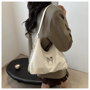 Detailed side view of white minimalist shoulder bag with large silver butterfly ornament