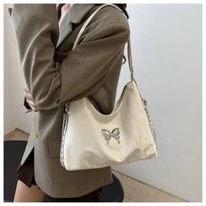 Detail of white pleated shoulder bag with silver butterfly buckle and chain strap