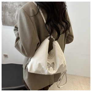Detail of white glossy shoulder bag with silver butterfly buckle and chain strap