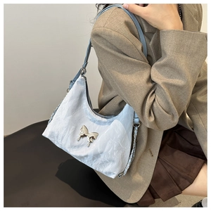 Detail of light blue wrinkled texture bag with silver butterfly and chain strap