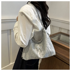Silver pleated shoulder bag with metal butterfly logo detail on female model