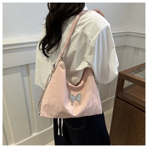 Detail of pink crescent bag featuring silver butterfly ornament and wrinkled texture