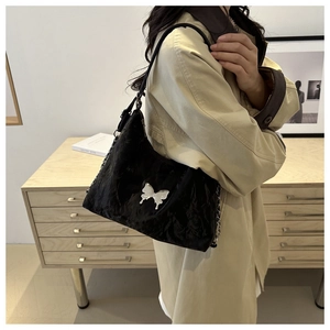 Close-up of black pleated texture shoulder bag with silver butterfly buckle detail