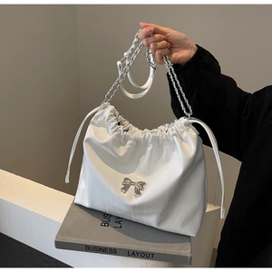 Dettaglio della borsa in pelle bianca con fiocco in metallo argento e pieghe
