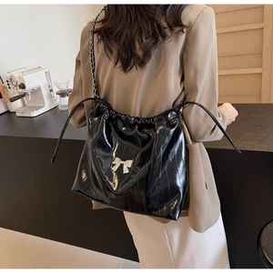 Dettaglio borsa tote in pelle verniciata nera lucida con fiocco argento e catena