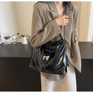 Dettaglio della borsa nera lucida con strisce verticali e un fiocco in argento decorativo